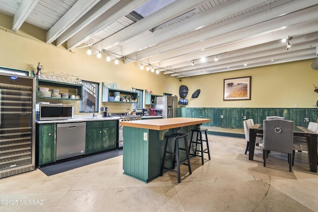 kitchen featuring wine cooler, a breakfast bar area, stainless steel appliances, open shelves, and green cabinetry