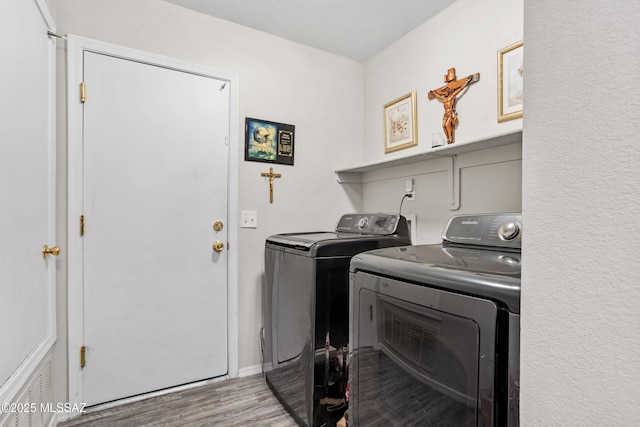 laundry area with laundry area, separate washer and dryer, and wood finished floors