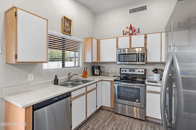 kitchen with wood finished floors, a sink, visible vents, light countertops, and appliances with stainless steel finishes