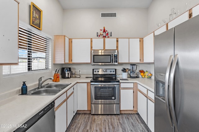 kitchen with visible vents, appliances with stainless steel finishes, wood finished floors, light countertops, and a sink