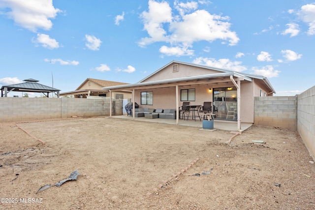 rear view of property with a gazebo, a patio area, a fenced backyard, and stucco siding