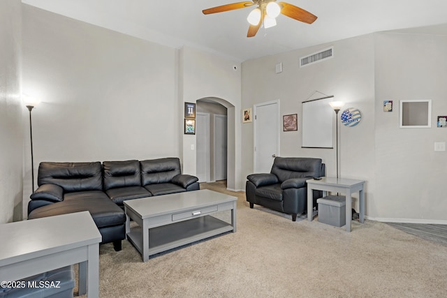 living room with arched walkways, carpet, visible vents, a ceiling fan, and baseboards