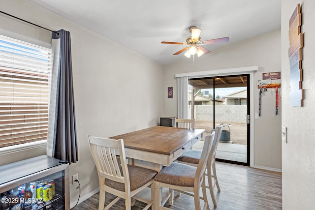 dining space with wood finished floors, a ceiling fan, and baseboards