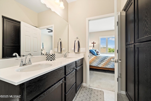 ensuite bathroom with tile patterned floors, connected bathroom, double vanity, and a sink