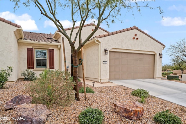 mediterranean / spanish house with a tiled roof, stucco siding, an attached garage, and driveway