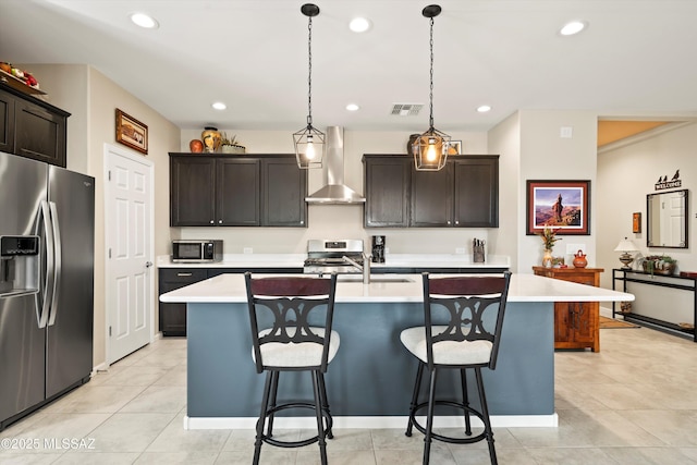 kitchen with light countertops, wall chimney range hood, a breakfast bar area, and appliances with stainless steel finishes