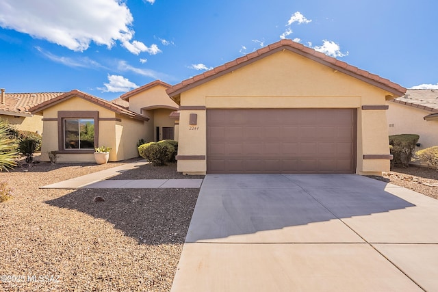 view of front of home with a garage, driveway, a tiled roof, and stucco siding