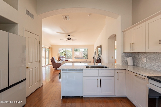 kitchen featuring a peninsula, visible vents, open floor plan, and dishwasher