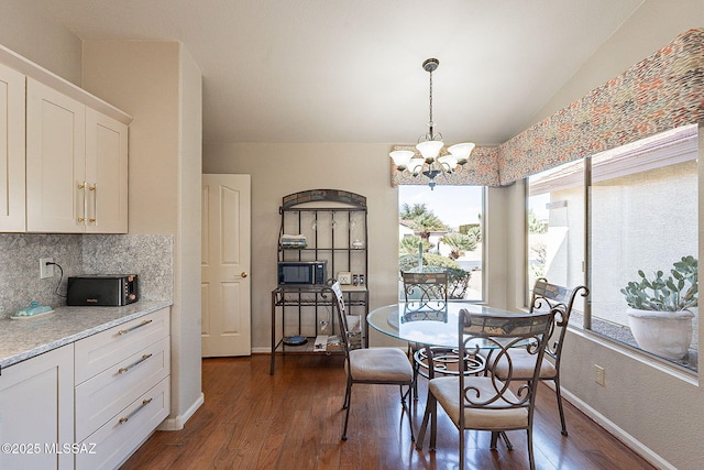 dining area with vaulted ceiling, dark wood-type flooring, baseboards, and an inviting chandelier