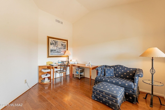 living area with vaulted ceiling, wood finished floors, visible vents, and baseboards