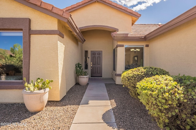 entrance to property featuring a tiled roof and stucco siding