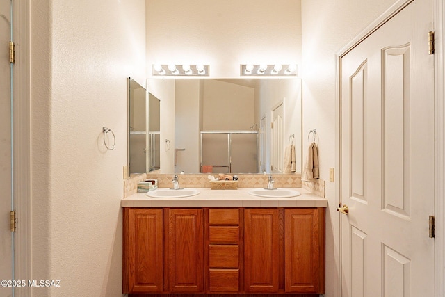 full bath featuring double vanity, a sink, and a shower stall