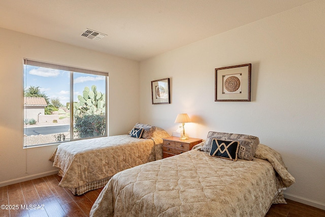 bedroom featuring wood finished floors, visible vents, and baseboards