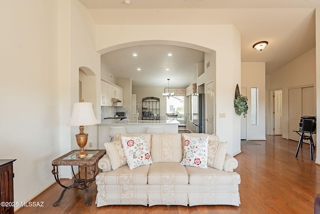 living area featuring a notable chandelier, baseboards, wood finished floors, and recessed lighting