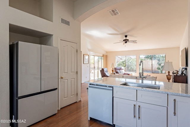 kitchen with visible vents, freestanding refrigerator, open floor plan, a sink, and dishwasher