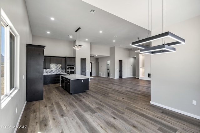 kitchen featuring visible vents, a center island with sink, wood finished floors, open floor plan, and light countertops