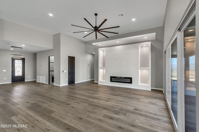 unfurnished living room featuring recessed lighting, visible vents, wood finished floors, and a glass covered fireplace