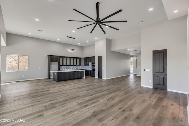 unfurnished living room featuring recessed lighting, ceiling fan, and a high ceiling