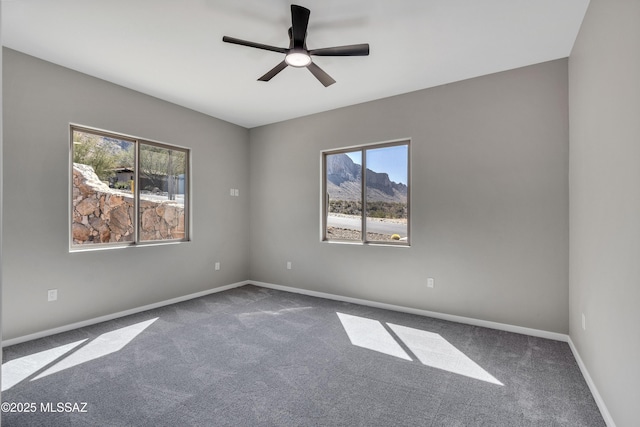 carpeted spare room with a ceiling fan and baseboards