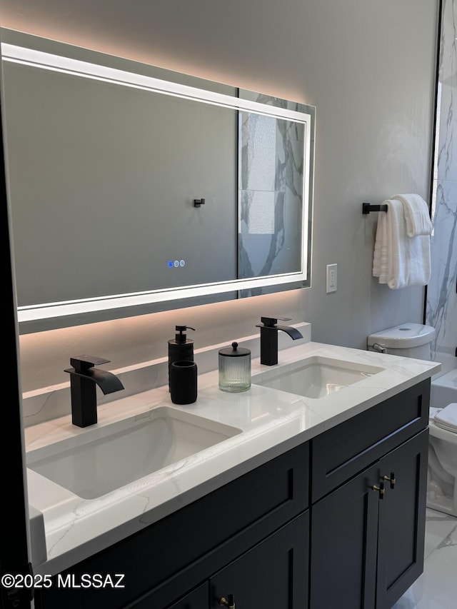 full bathroom with double vanity, marble finish floor, toilet, and a sink