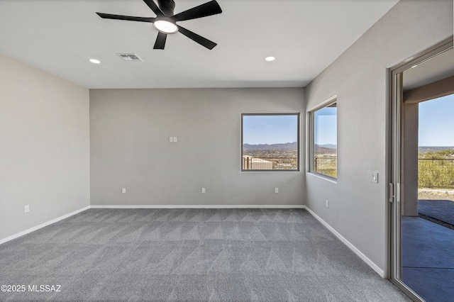 empty room featuring a healthy amount of sunlight, visible vents, dark carpet, and baseboards