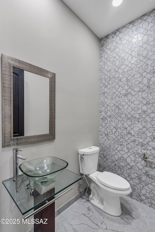 half bathroom featuring vanity, toilet, and marble finish floor