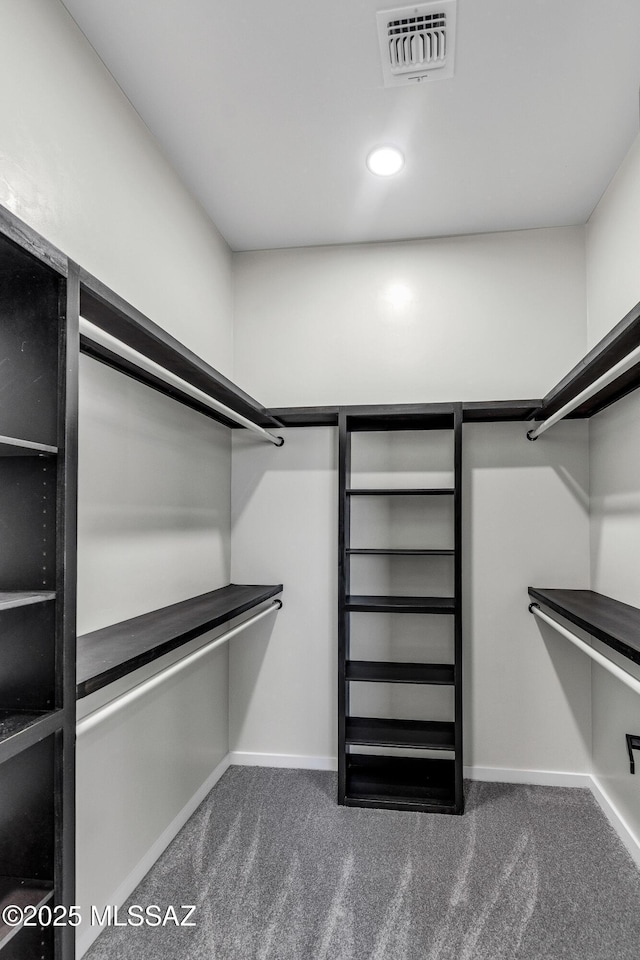 spacious closet featuring visible vents and dark colored carpet