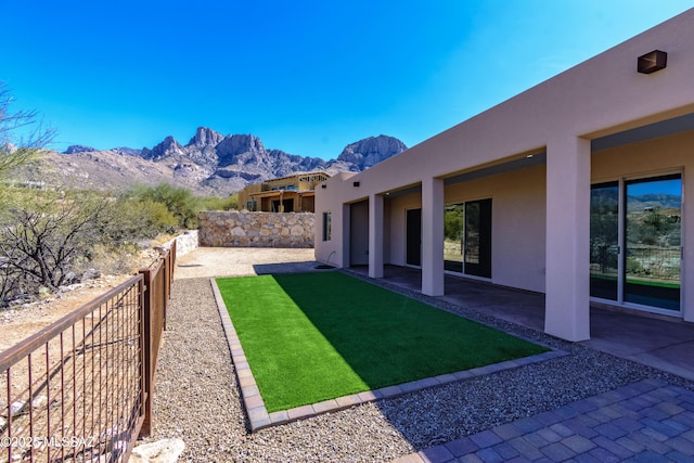 view of yard featuring fence, a mountain view, and a patio