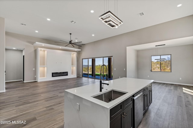 kitchen with visible vents, a sink, open floor plan, a glass covered fireplace, and stainless steel dishwasher