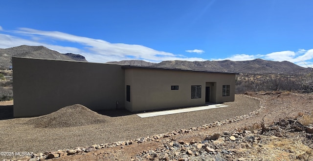 view of side of property with a mountain view and stucco siding