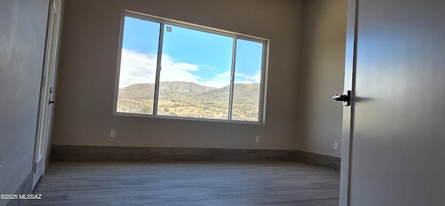 unfurnished room featuring wood finished floors and a mountain view