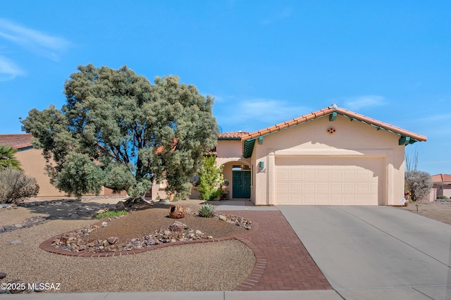 mediterranean / spanish-style house featuring a garage, concrete driveway, a tile roof, and stucco siding