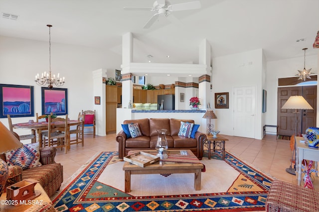 living area with high vaulted ceiling, ceiling fan with notable chandelier, visible vents, and light tile patterned floors