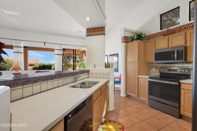 kitchen featuring light tile patterned floors, appliances with stainless steel finishes, a sink, and light brown cabinetry