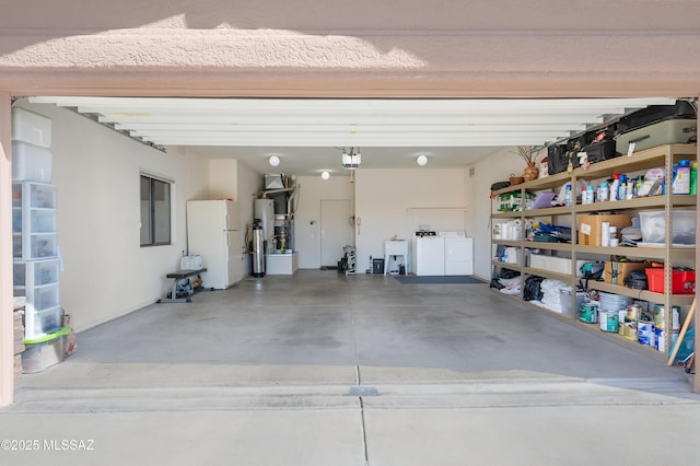 garage featuring gas water heater, a sink, freestanding refrigerator, a garage door opener, and washer and clothes dryer