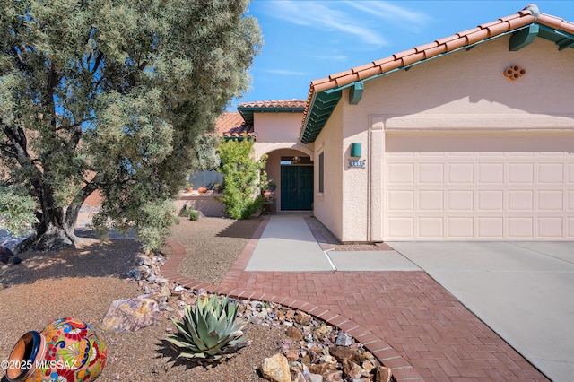 mediterranean / spanish house featuring an attached garage, a tile roof, concrete driveway, and stucco siding