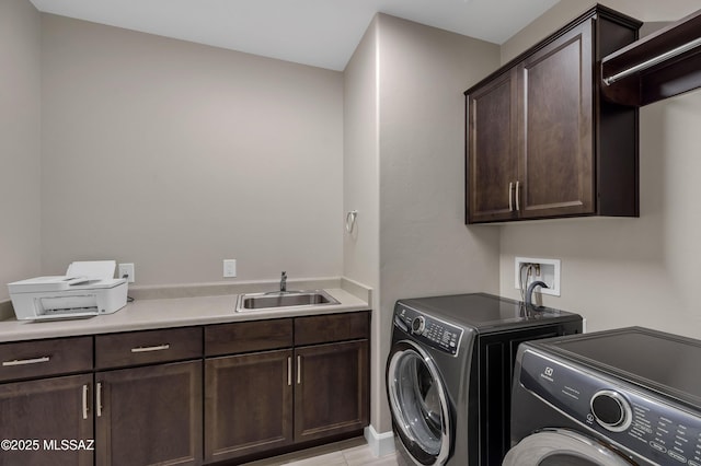 clothes washing area featuring washer and clothes dryer, cabinet space, and a sink