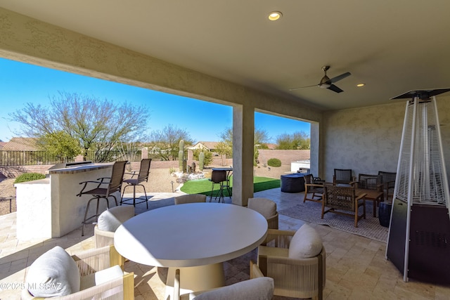 view of patio featuring an outdoor living space, outdoor dining area, a fenced backyard, ceiling fan, and outdoor dry bar