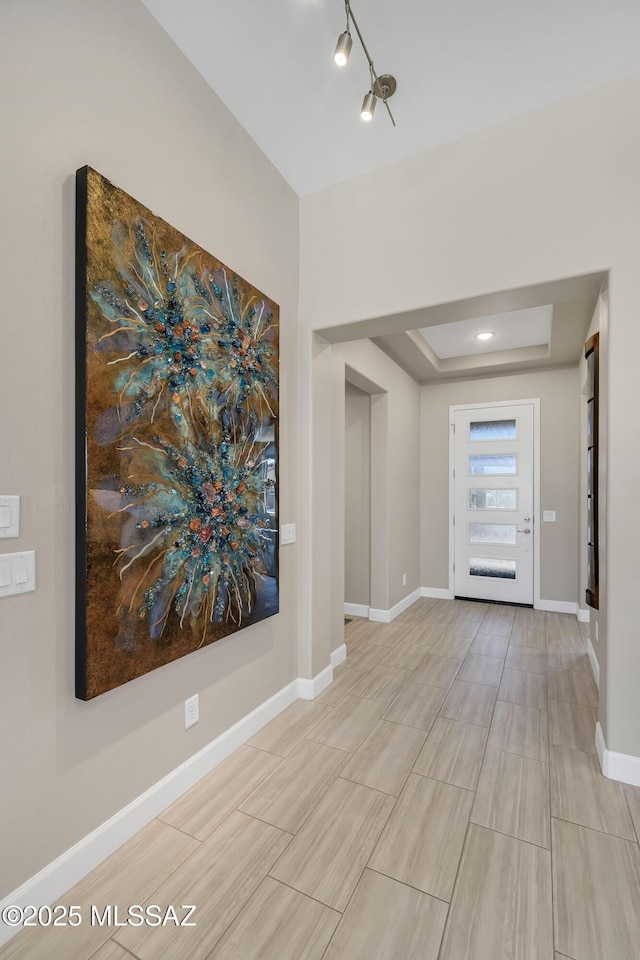 entrance foyer featuring a tray ceiling and baseboards