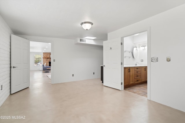 unfurnished room with a sink, visible vents, concrete flooring, and a fireplace