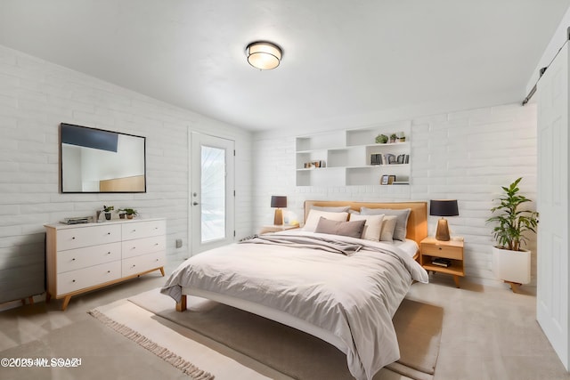 bedroom featuring access to exterior, light colored carpet, and brick wall