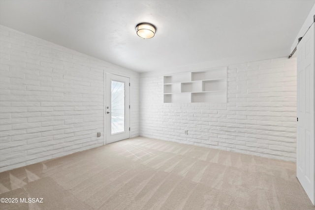 unfurnished room featuring carpet and brick wall