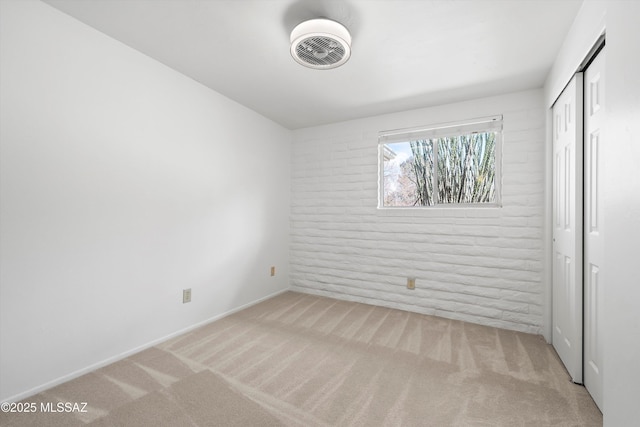 unfurnished bedroom featuring a closet, carpet floors, and brick wall