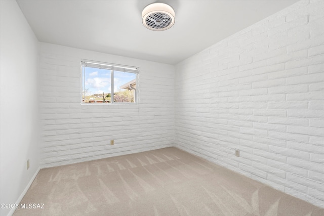 unfurnished room featuring carpet flooring, brick wall, and visible vents