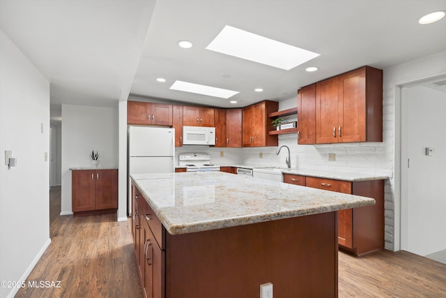 kitchen with tasteful backsplash, a sink, light wood-style flooring, white appliances, and open shelves