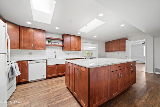 kitchen featuring a sink, open shelves, light wood-style floors, a skylight, and white dishwasher