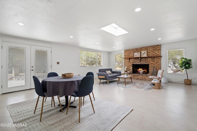 dining room featuring a brick fireplace, recessed lighting, french doors, and brick wall