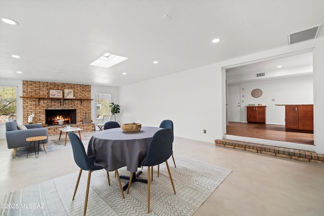 dining space with a brick fireplace, recessed lighting, visible vents, and finished concrete floors