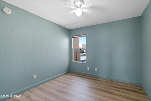 empty room featuring baseboards, wood finished floors, and a ceiling fan