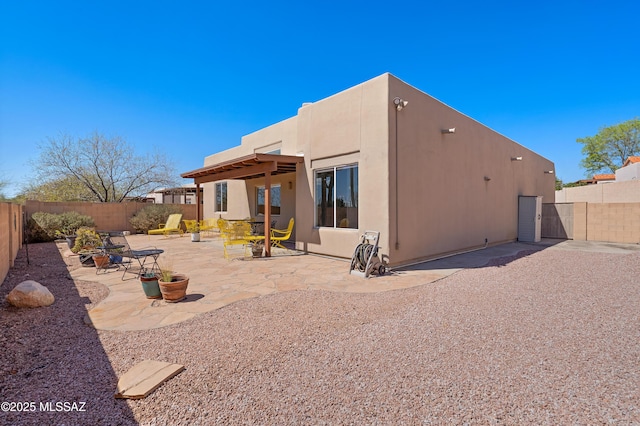 rear view of property with stucco siding, a patio, and a fenced backyard